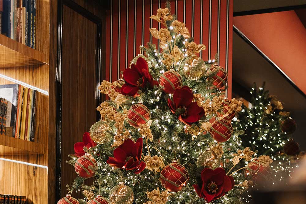Árvore de Natal verde-floresta decorada com enfeites vermelhos e dourados.