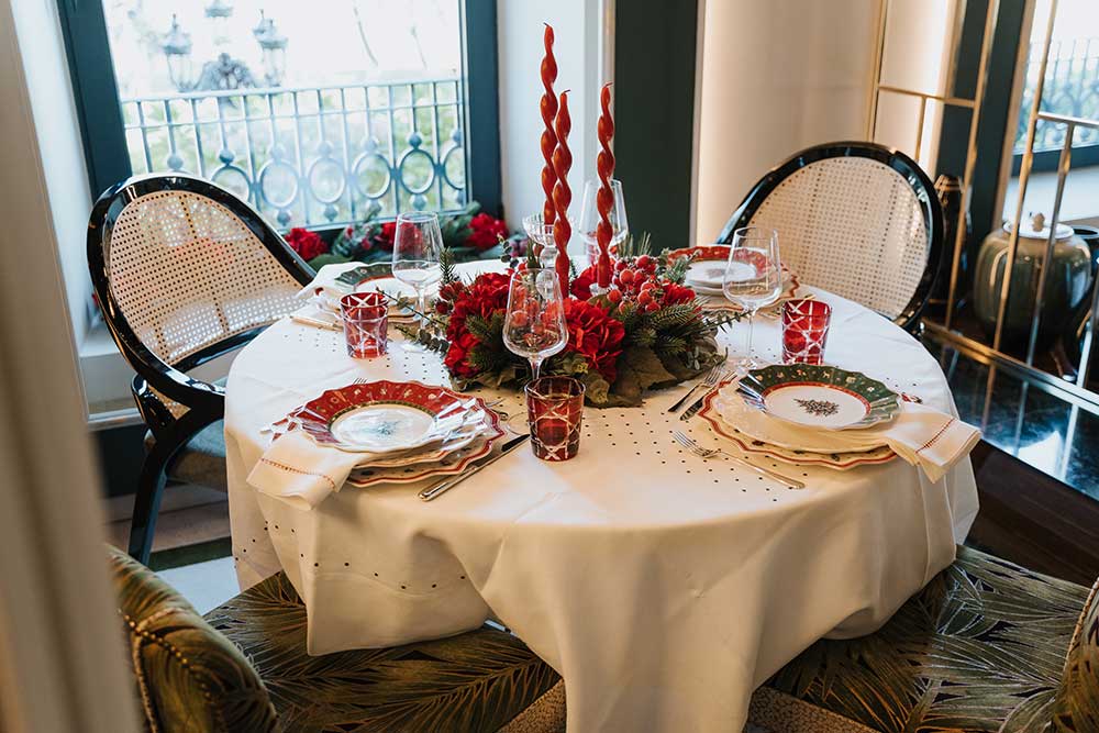 Mesa de Natal com serviço de mesa alusivo à época e coroa e velas no centro da mesa.