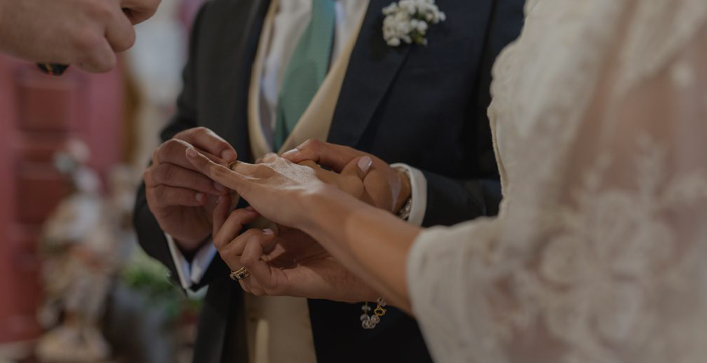 Noivo introduzindo aliança no dedo da noiva.